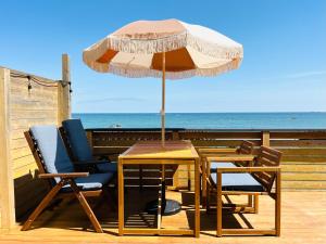 a table and chairs with an umbrella on a deck at PACIFICO SURF HOUSE - by the Sea in Shishikui