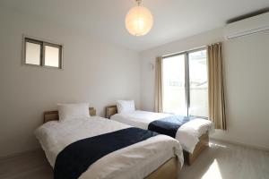 two beds in a room with a window at King's House in Osaka
