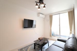 a living room with a couch and a tv on a wall at King's House in Osaka