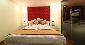 Kawasaki Noi Bai Hotel في Noi Bai: غرفة نوم بسرير كبير مع اللوح الأمامي الأحمر