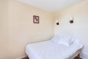 - une chambre avec un lit blanc et deux lumières sur le mur dans l'établissement Résidence Quartier Falaise - maeva Home - Appartement 2 pièces 4 personnes 754, à Avoriaz