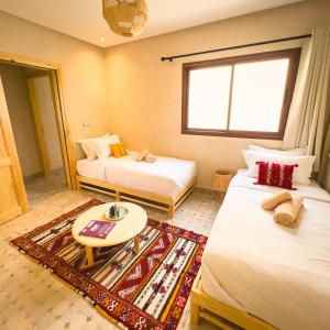 Habitación de hotel con 2 camas y mesa en The Moroccan Surf House, en Imsouane