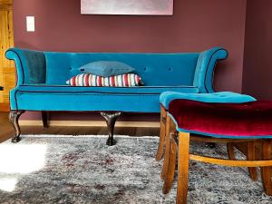 a blue couch in a living room with a stool at Ferienappartment "Beim Schmied" in Chiemseenähe in Traunreut