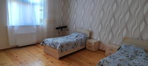 1 dormitorio con 2 camas, ventana y suelo de madera en Kirayə ev, Qax, Qaşqaçay guesthouse, en Qax