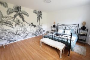 um quarto com uma cama preta e um mural de palmeiras em M&A maison de campagne/ Disney/Paris/Wifi/Jeux em Croissy-Beaubourg