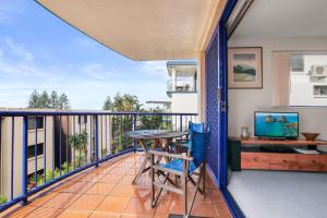 un balcone con tavolo, sedie e TV di Jade Waters U4 5 Latona Ave a Caloundra