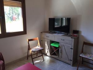 a living room with a television on a dresser with two chairs at Kosmarana skopelos realty in Loutraki