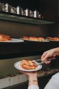 a person holding a plate of pastries on shelves at Hotel Zaragoza Plaza in Donostia-San Sebastián
