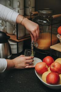 a person pouring a drink into a glass next to a plate of apples at Hotel Zaragoza Plaza in Donostia-San Sebastián