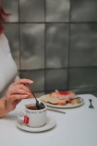 a woman is stirring a cup of coffee with a spoon at Hotel Zaragoza Plaza in Donostia-San Sebastián