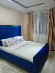 uma cama com uma cabeceira azul num quarto em Atalia Athi River em Nairobi