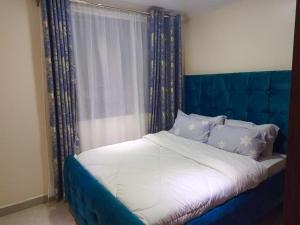 uma cama com uma cabeceira azul num quarto em Atalia Athi River em Nairobi