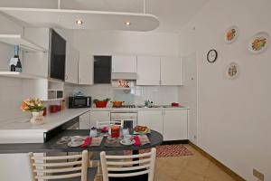 eine Küche mit weißen Schränken sowie einem Tisch und Stühlen in der Unterkunft Il Glicine Di Anna - Happy Rentals in Gignese