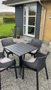 a picnic table and two chairs in front of a house at Værelser i Fynshav in Augustenborg