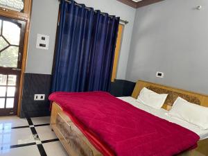 um quarto com uma cama com um cobertor vermelho em Abhi Homestay em Khajjiar 