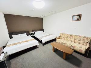 a hotel room with two beds and a couch at グリーンホテル会津 in Aizuwakamatsu