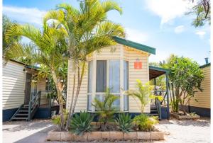 a yellow house with palm trees in front of it at Discovery Parks - Carnarvon in Carnarvon