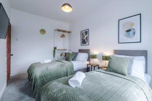 1 Schlafzimmer mit 2 Betten und grüner und weißer Bettwäsche in der Unterkunft Beautiful Pontefract House w/ Parking Sleeps 12 by PureStay in Pontefract