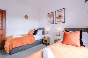 a bedroom with two beds with orange pillows at Beautiful Pontefract House w/ Parking Sleeps 12 by PureStay in Pontefract