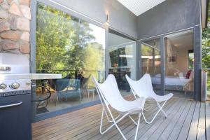 a patio with white chairs and a table on a deck at Hygge in Harrietville