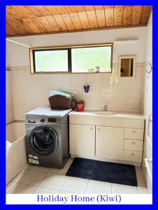 Swanson的住宿－西奧克蘭浪漫懷舊度假屋，小型浴室设有洗衣机和水槽。