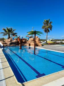 a swimming pool at a resort with palm trees at Camping Resort Els Pins in Malgrat de Mar