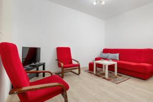 a living room with a red couch and two chairs at Older Krab in Rewal