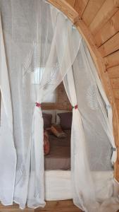 1 cama con cortinas blancas en una cabaña de madera en Coin exotique Villa CasaEva en Porto Vecchio