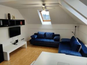 a living room with a blue couch and a tv at Sunshine apartment Bled in Bled