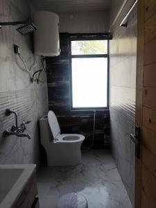 a small bathroom with a toilet and a window at Hotel Badrinath in Badrinath
