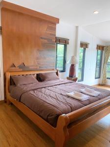 Ban Nong Pa Kha的住宿－บ้านสวนภูรจิตร Baansuanphurajit，卧室内的一张带木制床头板的大床