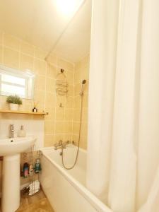 a bathroom with a shower and a tub and a sink at Cosy Luxurious 3 Bedroom House, Free Parking, Free WiFi, Private Garden, Free Netflix in Havering atte Bower
