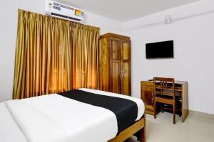 a bedroom with a bed and a dresser and a television at OYO Timber Near Lulu Mall in Trivandrum