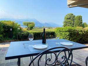 een blauwe tafel met twee glazen en een fles wijn bij Flowers and garden apartment in Manerba del Garda