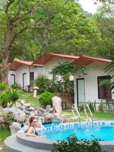 a child sitting in a pool in front of a house at Tran Chau Garden Home in Cat Ba