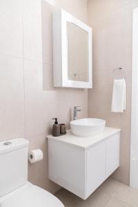 Un baño blanco con lavabo y espejo. en Venus Apartment, en Lárnaca 7 fotos más