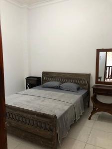 Schlafzimmer mit einem Bett mit einem Holzrahmen und einem Spiegel in der Unterkunft Jasmine Homestay Syariah in Jepara