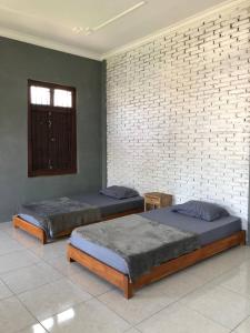 two beds in a room with a brick wall at Jasmine Homestay Syariah in Jepara