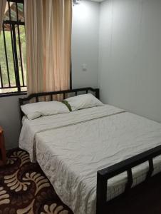 una camera da letto con un letto con lenzuola bianche e una finestra di Nyakach Getaway Kisumu a Kap Sarok