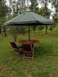 stół i dwa krzesła pod parasolem w obiekcie Nyakach Getaway Kisumu w mieście Kap Sarok