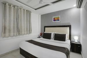 um quarto com uma cama com paredes brancas e uma janela em Super OYO Hotel Mannat Near Lotus Temple em Nova Deli