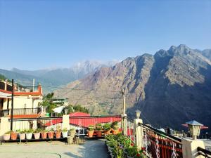 a building with a fence and mountains in the background at Hotel Joshimath Inn in Joshīmath