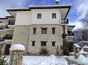 un grand bâtiment en pierre avec de la neige au sol dans l'établissement Hotel Kokkinos Vrachos, à Elati