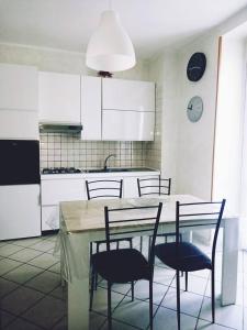una cocina con mesa y sillas y una cocina con armarios blancos. en Pasubio House casa vacanze, en Campobasso