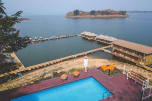 a man standing next to a swimming pool next to a body of water at ภูไพรเลค รีสอร์ท in Ban Wang Khun Knachen