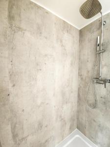 a shower in a bathroom with a concrete wall at W Ogrodzie Dla Gości in Sasino
