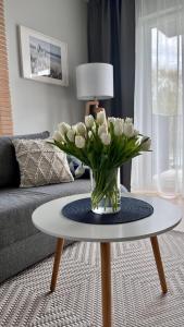 een vaas met witte bloemen op een tafel in een woonkamer bij Apartament Seaside Dune - Aleja Południowa 14A Dźwirzyno in Dźwirzyno