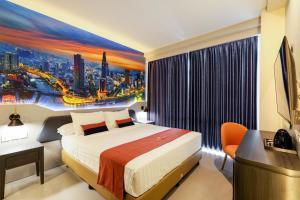 a hotel room with a bed and a painting of a city at Azana Style Hotel Tulungagung in Tulungagung