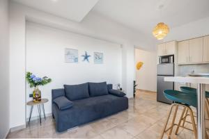 a living room with a blue couch and a kitchen at Celeste Junior Suite on the Beach in Nea Kydonia