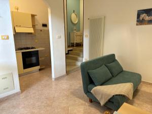 a living room with a green chair and a kitchen at Villa Bucchi in Lido di Spina